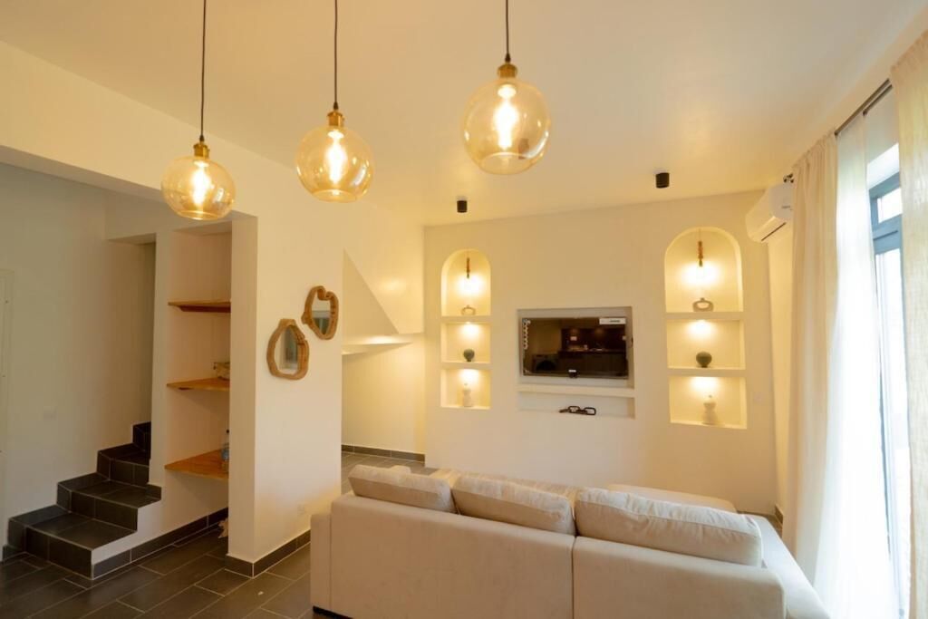 Una sala de estar moderna con sofá, estanterías empotradas e iluminación colgante.