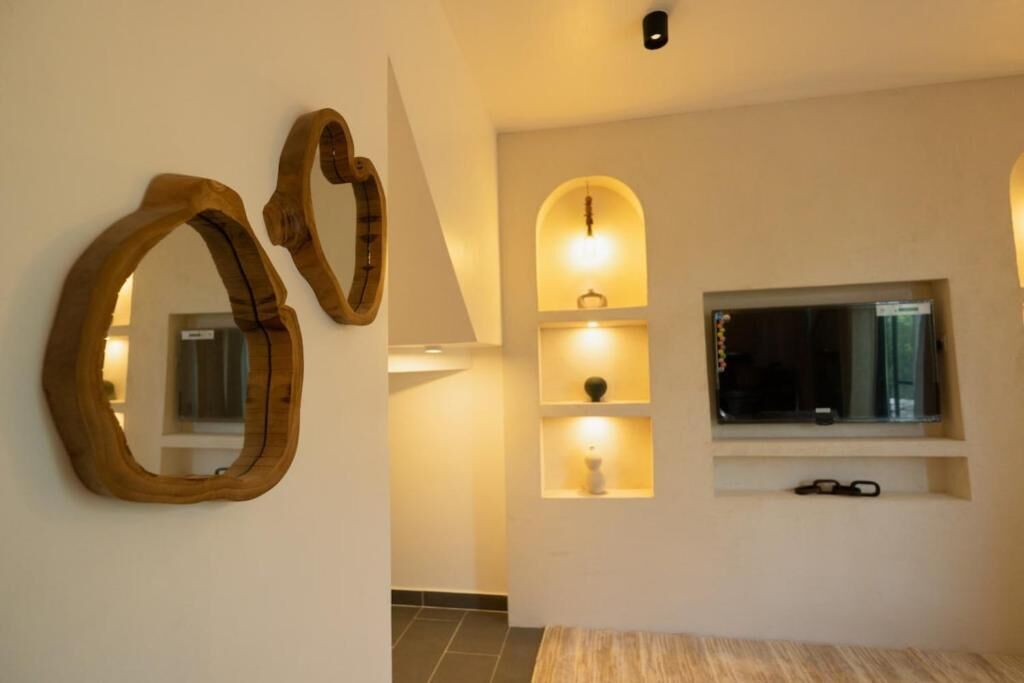 Ein modernes Interieur mit einem hölzernen herzförmigen Spiegel, einem an der Wand montierten Fernseher und Einbauschränken mit Beleuchtung.