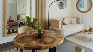 A modern living room with a round wooden coffee table, a beige sofa, and a large mirror. - Nafsi Nomad (Paje)