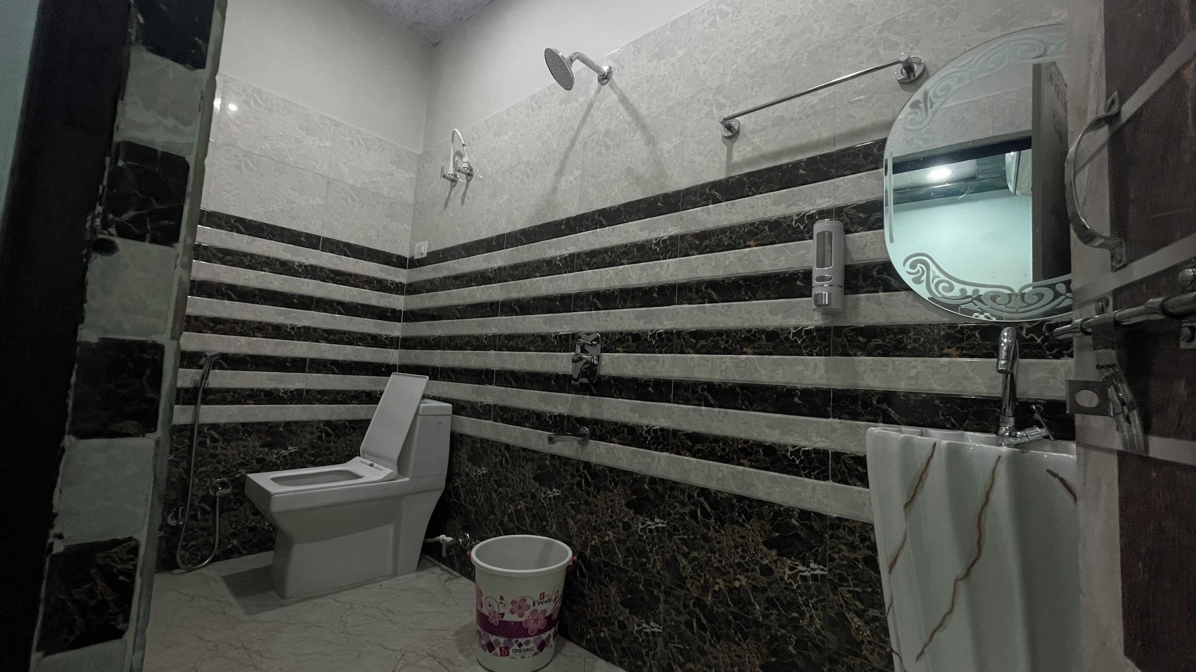 A bathroom with a toilet, a shower, and a sink.
