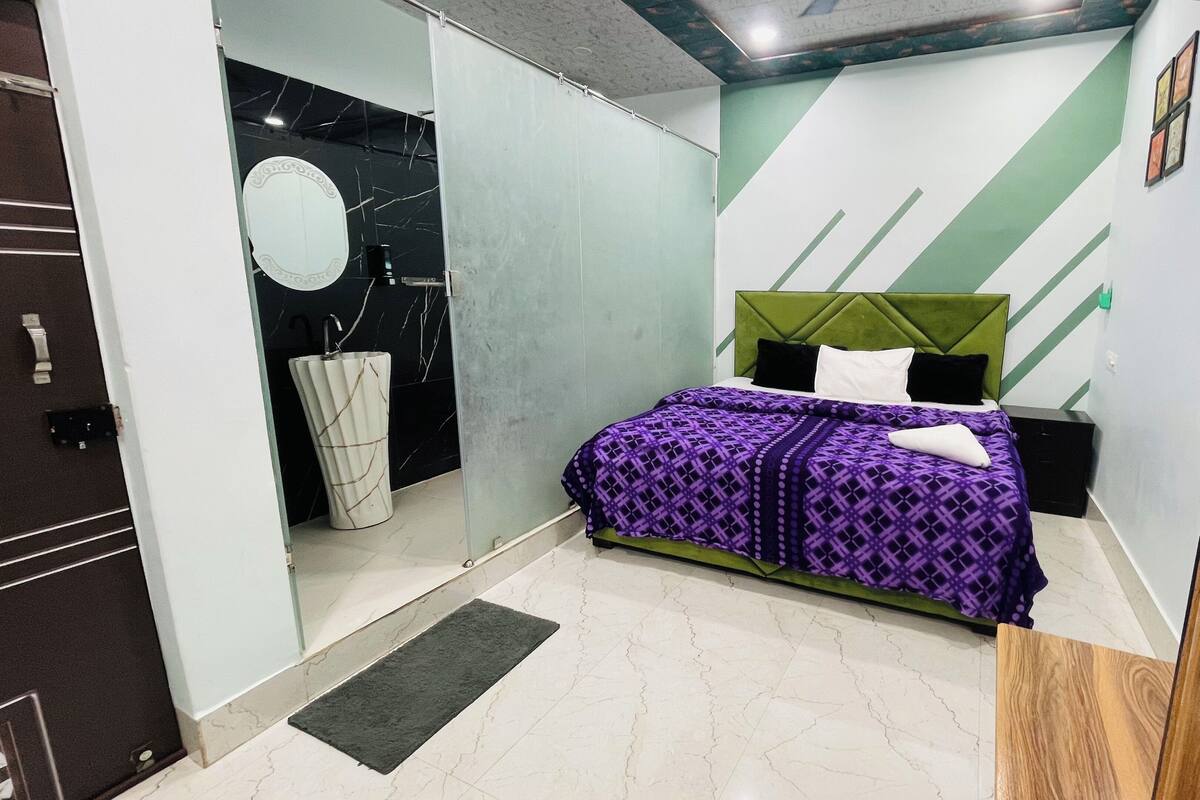 Une chambre à coucher moderne avec un lit, une table de chevet, un miroir et une porte.