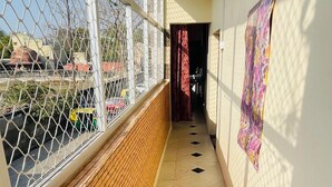 Un couloir doté d’un sol carrelé, d’un mur en bois d’un côté et d’une clôture en treillis métallique de l’autre.