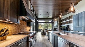 Een moderne keuken met een bakstenen muur, roestvrijstalen apparatuur en houten aanrechtbladen.