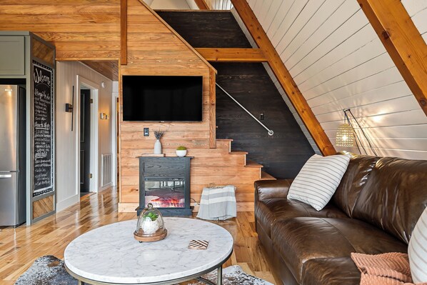 Una sala de estar moderna con chimenea, un sofá de cuero marrón y una mesa de centro de mármol.