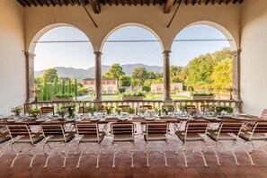 A dining area with a view of a landscaped garden and mountains. - Villa Antica in Lucca (Capannori)