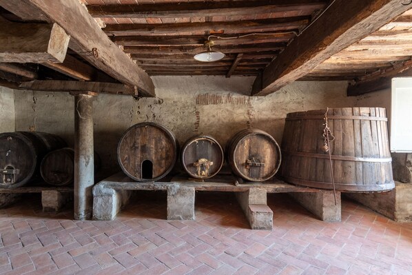A rustic cellar with wooden barrels and a brick floor. - Villa Antica in Lucca (Capannori)