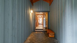 Un pasillo con un banco de madera, una puerta que da a una habitación y una lámpara en la pared.