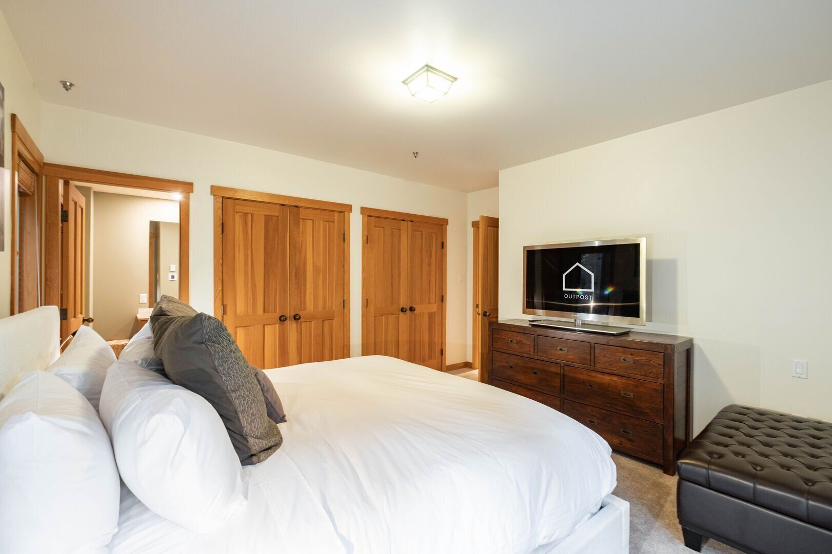 Een slaapkamer met een bed, een televisie, houten kasten en een dressoir.
