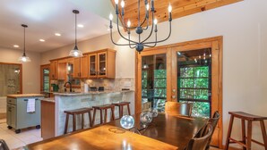 A spacious kitchen with wooden cabinets, a central island, and pendant lighting. - New Listing! Mtn Cabin: Fire pit, Hot tub Views (Cherry Log)