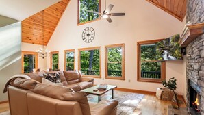 A spacious living room with a high ceiling, large windows, a fireplace, and a cozy seating area. - New Listing! Mtn Cabin: Fire pit, Hot tub Views (Cherry Log)