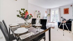 Un coin repas avec une table dressée pour quatre personnes, une bibliothèque et un télescope en arrière-plan.
