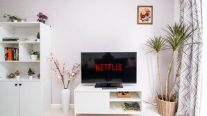 Un salon avec un meuble de rangement blanc pour l’équipement audiovisuel, un téléviseur à écran plat et une bibliothèque.