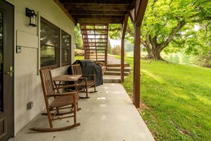 A covered patio with a table and chairs, a grill, and a view of a green lawn and trees. - 4 BR Cabin near Banner Elk/Beech Mtn. Hot Tub, Fire Pit & Yard (Banner Elk)
