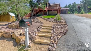 A two-story house with a wooden deck and a garage. - Our Comfy Cabin | Cozy Retreat w/ Foosball, Wildlife Views & Family Fun (Ruidoso)