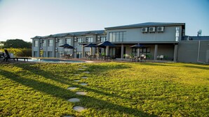 A modern hotel with a pool, outdoor seating, and a well-maintained lawn. - Two Rivers Hotel (Kasane)