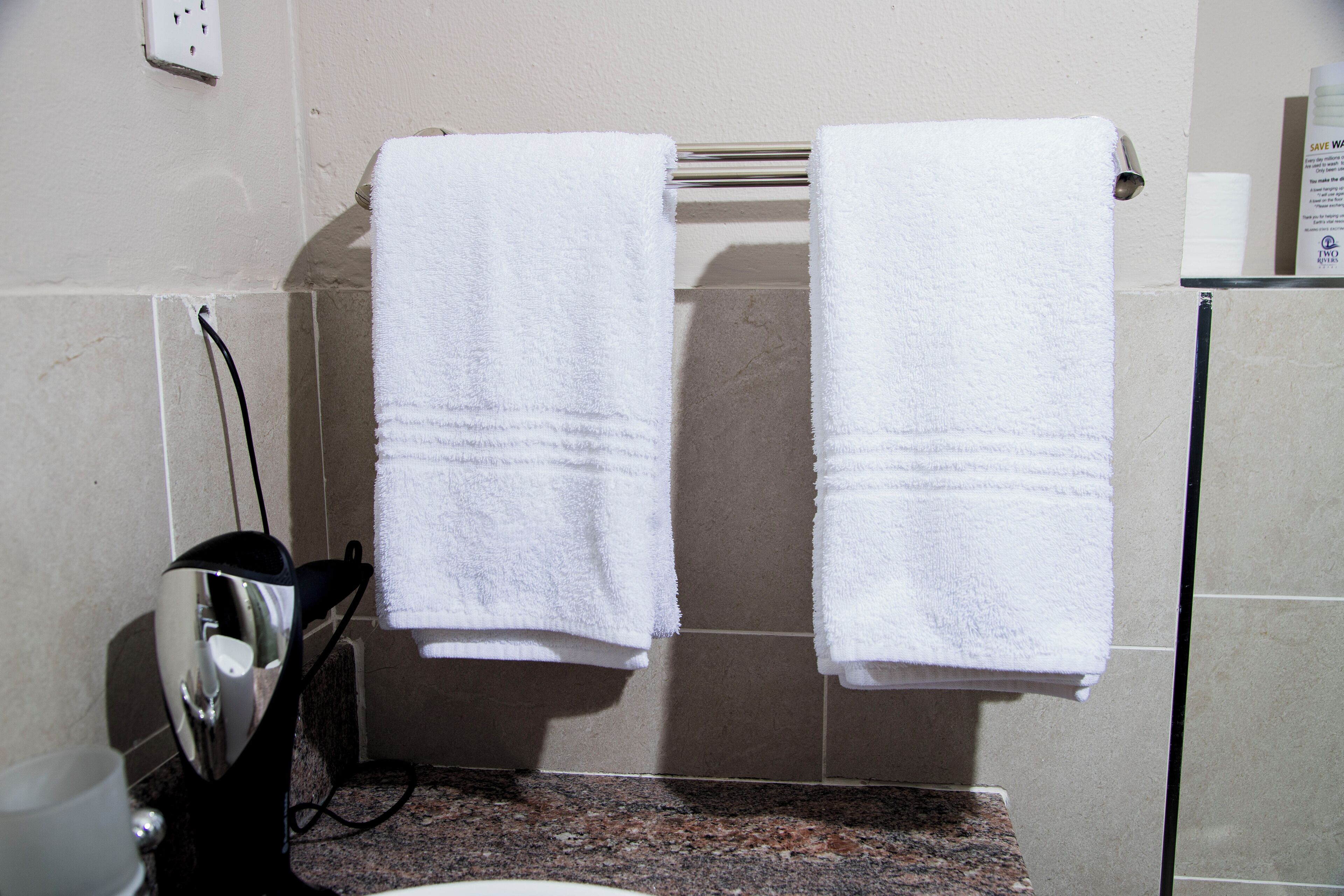 A bathroom with two white towels hanging on a rack, a sink, and a mirror.