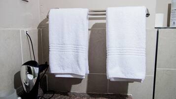 A bathroom with two white towels hanging on a rack, a sink, and a mirror.