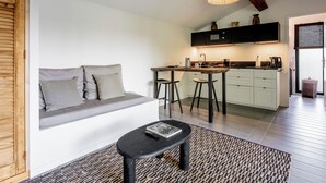 A modern kitchen with a dining area, a built-in bench with cushions, and a small table with a book. - La Cabane du Cap (Aix-en-Provence)