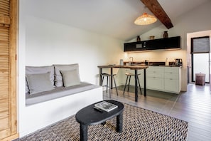 A modern kitchen with a dining area, a built-in bench with cushions, and a small table with a book. - La Cabane du Cap (Aix-en-Provence)