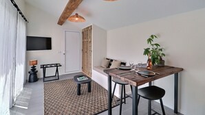 A modern dining area with a wooden table, black chairs, and a woven ceiling light fixture. - La Cabane du Cap (Aix-en-Provence)