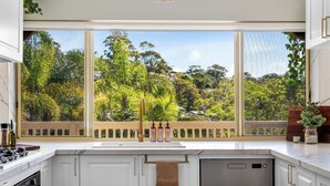 Een moderne keuken met een groot raam, witte kasten en een roestvrijstalen vaatwasser.