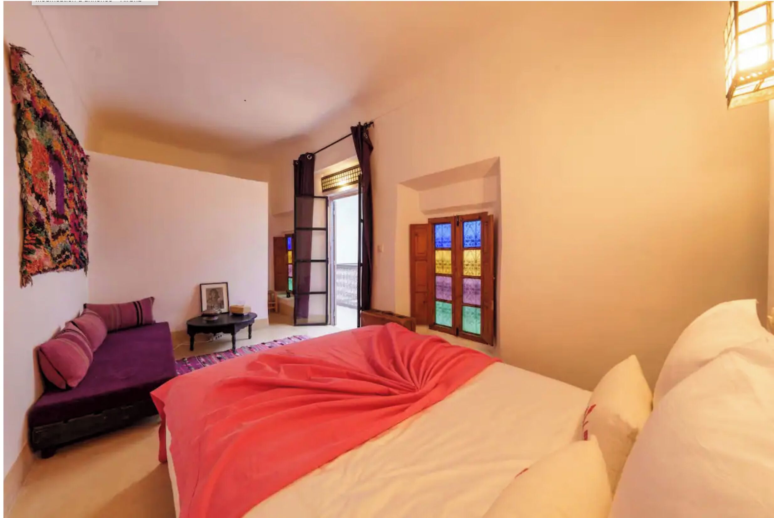 Een slaapkamer met een bed, een bank, een tafeltje en een raam met gordijnen.