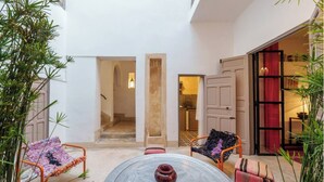 A courtyard with a round table, two chairs, and a small rug. There are two doors leading to other rooms, and a plant is visible on the left. - Exclusive charming riad in the heart of the medina

10 mn from Jemaa el fna  (Marrakech)