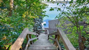 Eine Holztreppe führt zu einem Steg über dem Wasser, umgeben von Bäumen.