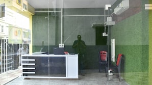 A reception desk with a computer, a telephone, and a chair. - MM Hotel and Service Apartment (Kolkata)