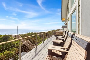 A wooden deck with outdoor seating overlooking a coastal view.