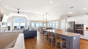 Un'ampia cucina con una grande isola, pavimento in legno e vista sull'oceano.