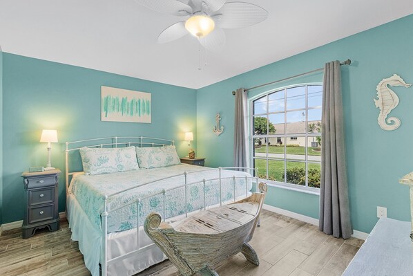 A bedroom with a bed, nightstands, a hanging chair, a ceiling fan, and a window with curtains. - Perfect Sunsets, Kayak, Bikes, Game Room, Heated Pool and Spa - Villa Adele- Roelens (Cape Coral)