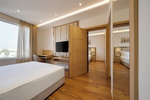 Una habitación de hotel moderna con una cama grande, un escritorio con televisor de pantalla plana, un armario y una pequeña zona de estar.