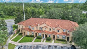 A multi-story building with a red-tiled roof, multiple windows, and a well-maintained lawn. - Family escape near Disney parks w/ resort access (Kissimmee)