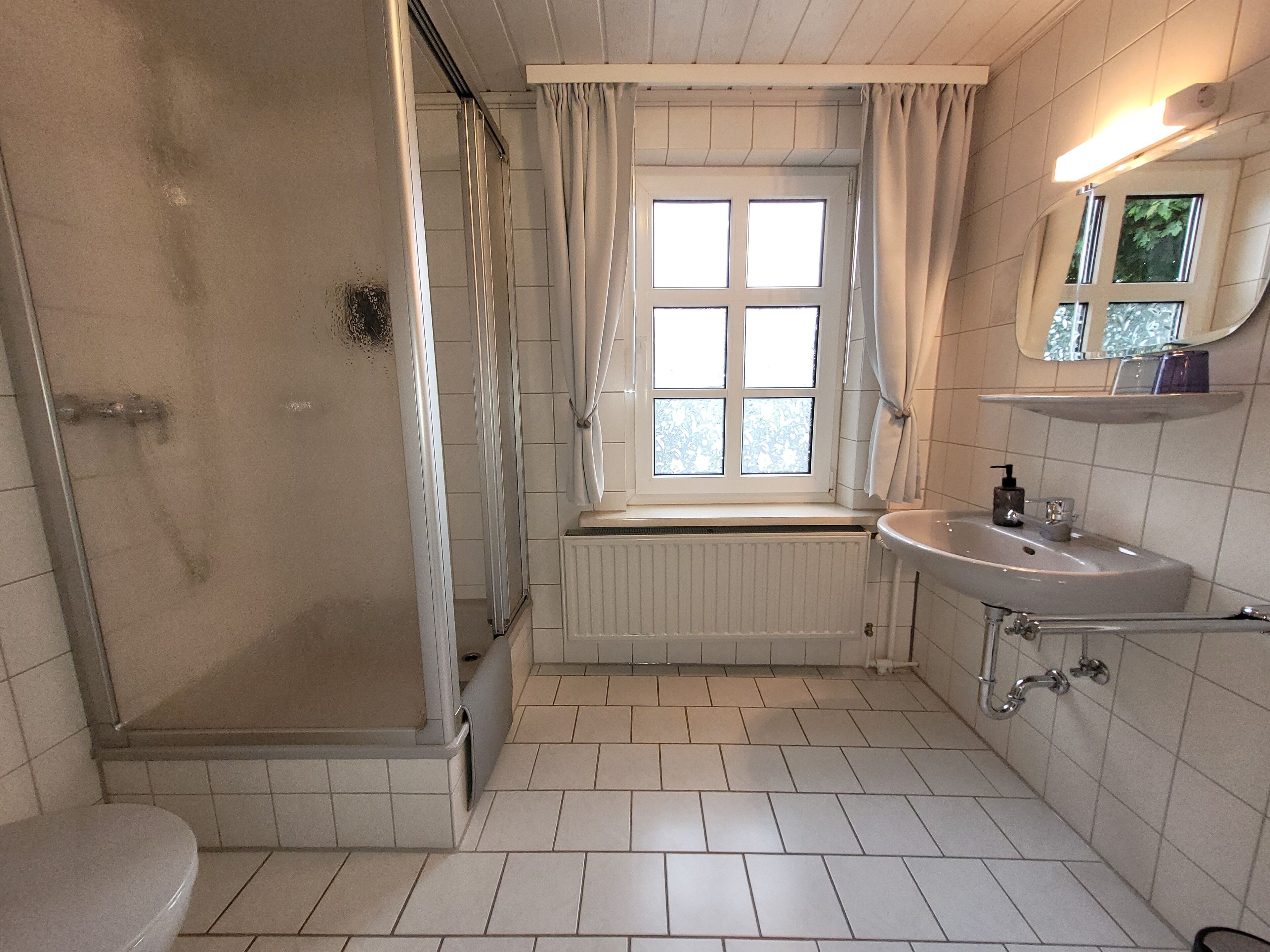 Un baño con ducha, inodoro, lavabo y ventana.