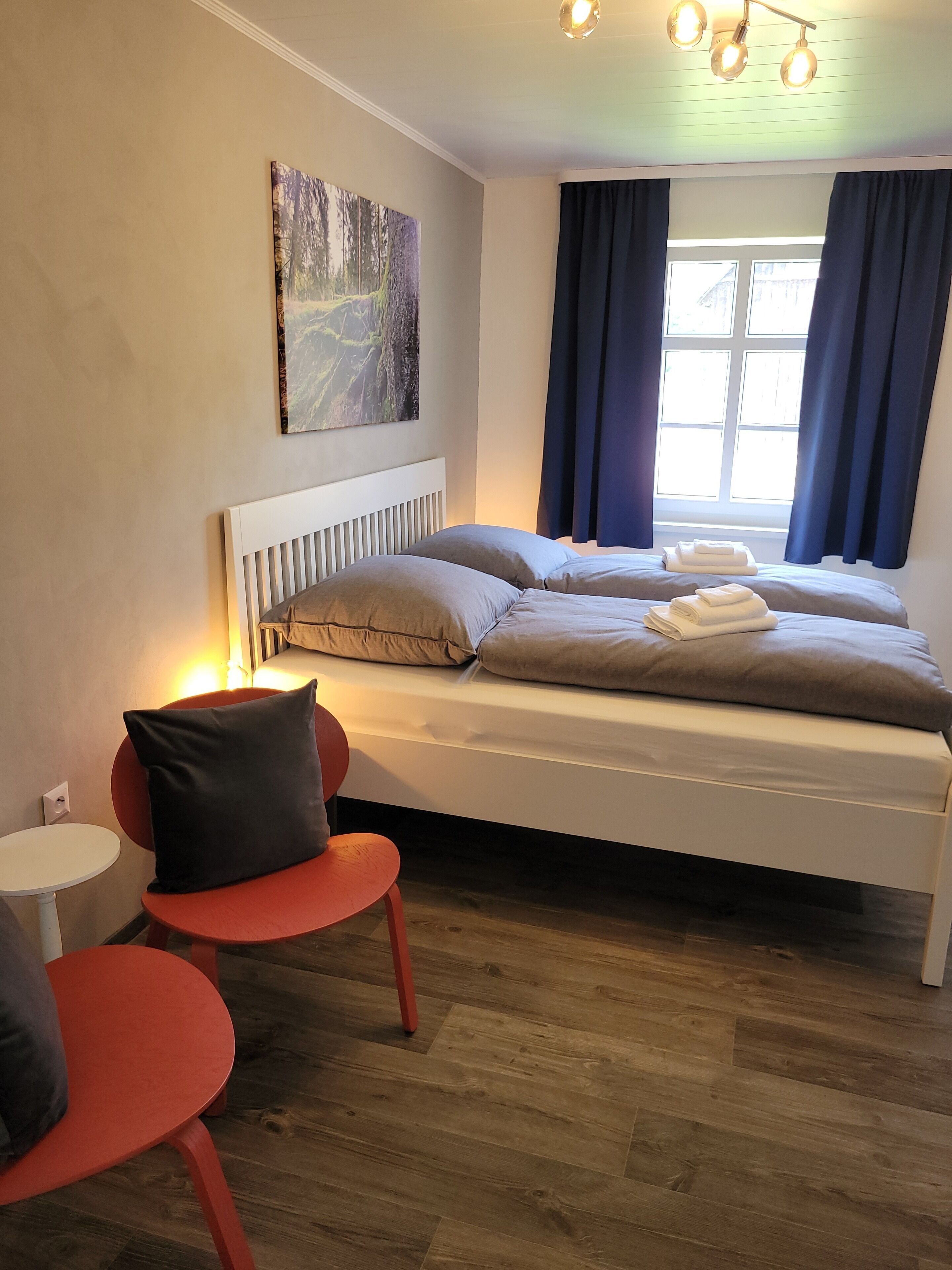 Ein modernes Schlafzimmer mit einem Bett, einem kleinen Tisch und einem Sessel.