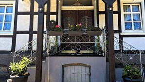A building with a sign reading "VINEU bed & breakfast" under a covered porch with wrought iron railings and potted plants. - VINEU - Bed n Breakfast (Winterberg)