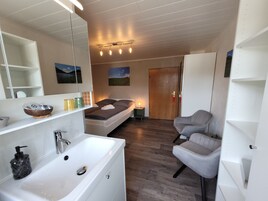 Ein modernes Badezimmer mit einem großen weißen Waschbecken, einem Spiegel und einem Holzboden.