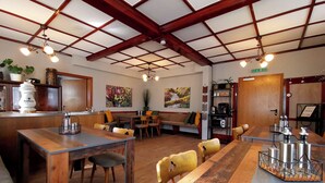 A restaurant with wooden tables and chairs, a bar area, and artwork on the walls. - VINEU - Bed n Breakfast (Winterberg)