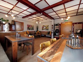 Ein Restaurant mit Holztischen und -stühlen, einer Bar und Bildern an den Wänden.