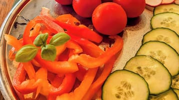 Una mesa de buffet con diversos alimentos, incluyendo pepinos en rodajas, tomates cherry y palitos de zanahoria.