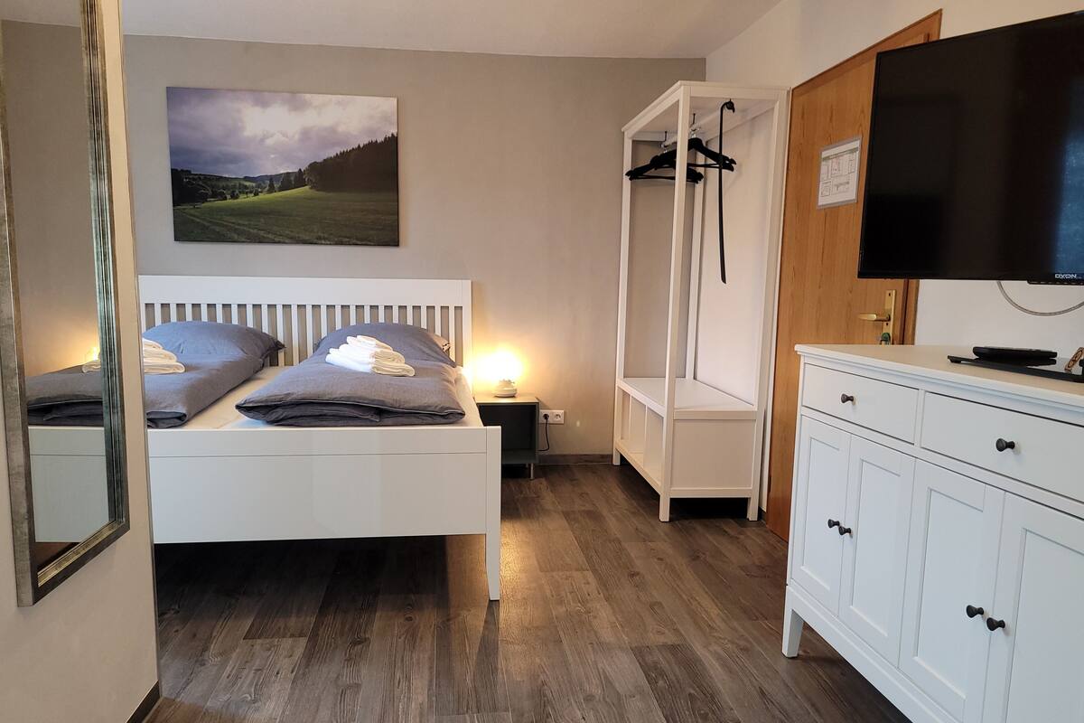 Une chambre à coucher avec un lit, une table de chevet et un téléviseur.