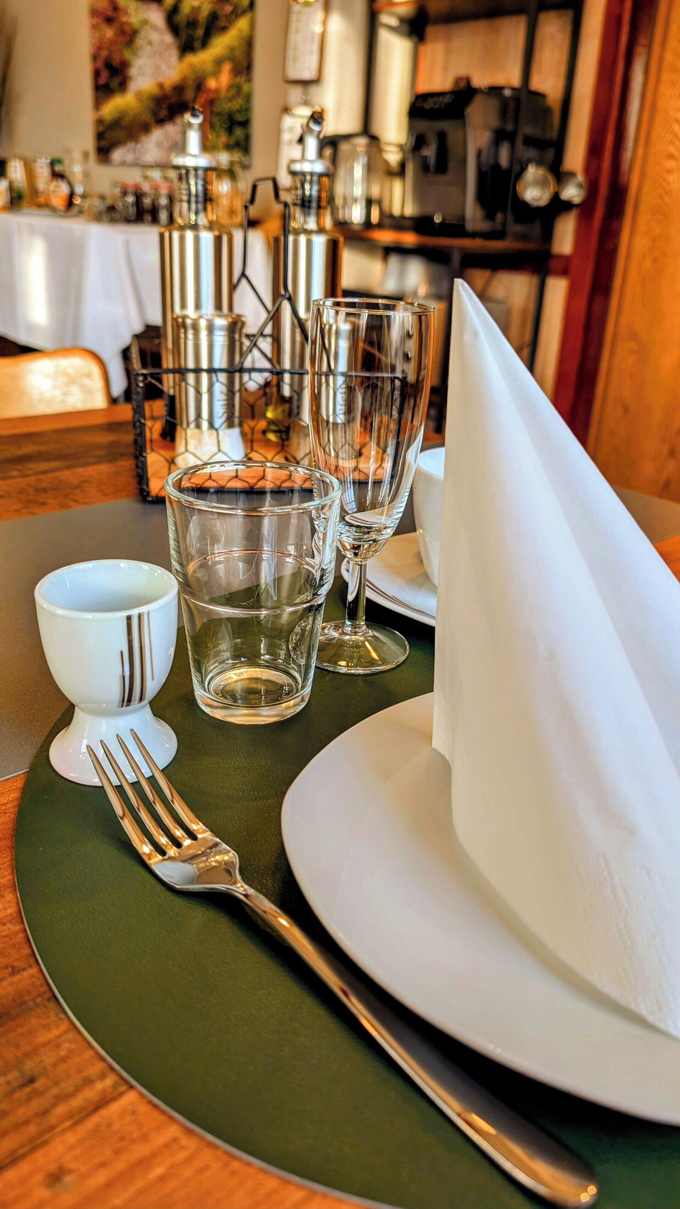 Una mesa de comedor dispuesta con un plato blanco, una servilleta doblada, un tenedor y dos vasos de agua.