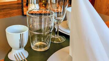 Una mesa de comedor dispuesta con un plato blanco, una servilleta doblada, un tenedor y dos vasos de agua.