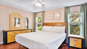 Une chambre Ă coucher avec un lit, une commode, un miroir et une fenĂȘtre avec des rideaux.