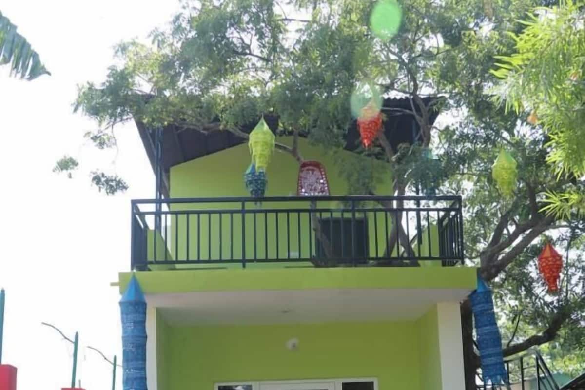 A two-story building with a green facade, a balcony, and a small entrance.