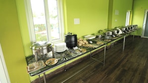 A buffet setup with multiple serving stations, a large black pot, and various dishes and utensils. - SandPebbles Bhitarkanika Jungle Resorts (Rajnagar)