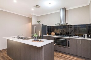 A modern kitchen with a central island, stainless steel appliances, and dark tiled backsplash. - Family Friendly 4BR Home - Free Parking, Fast WiFi (Jane Brook)