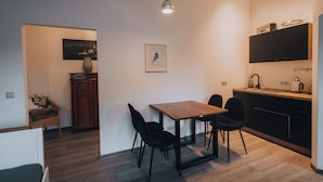 A modern kitchen with a wooden table, black chairs, and a hanging light fixture.