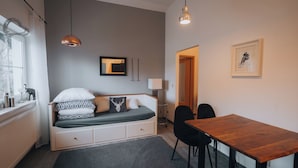 A compact room with a bed, a wooden table, and two chairs.